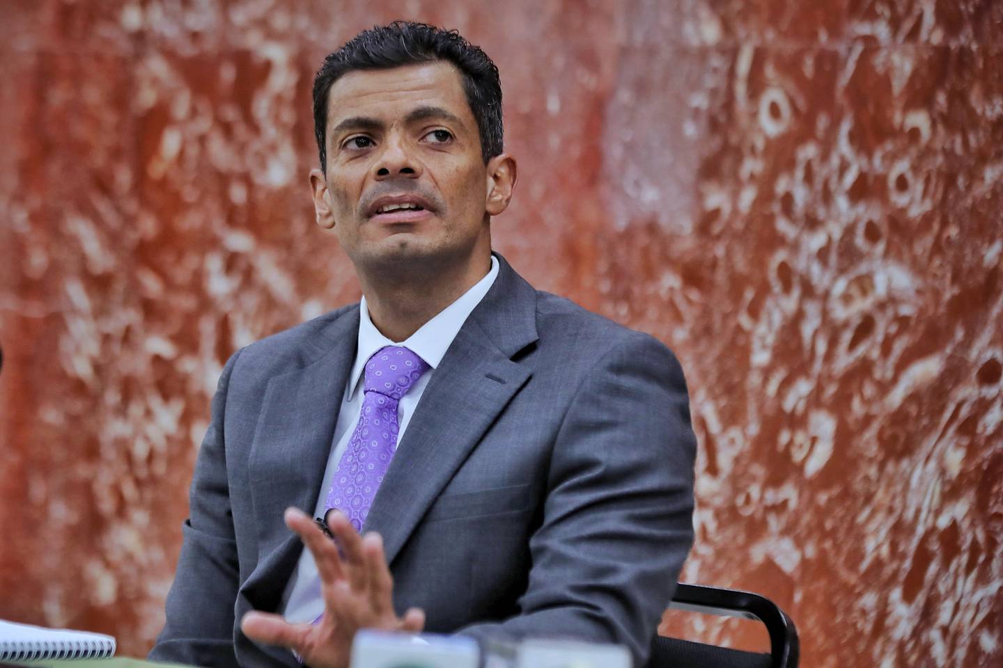 Un hombre sentado con un traje de color negro
Descripción generada automáticamente